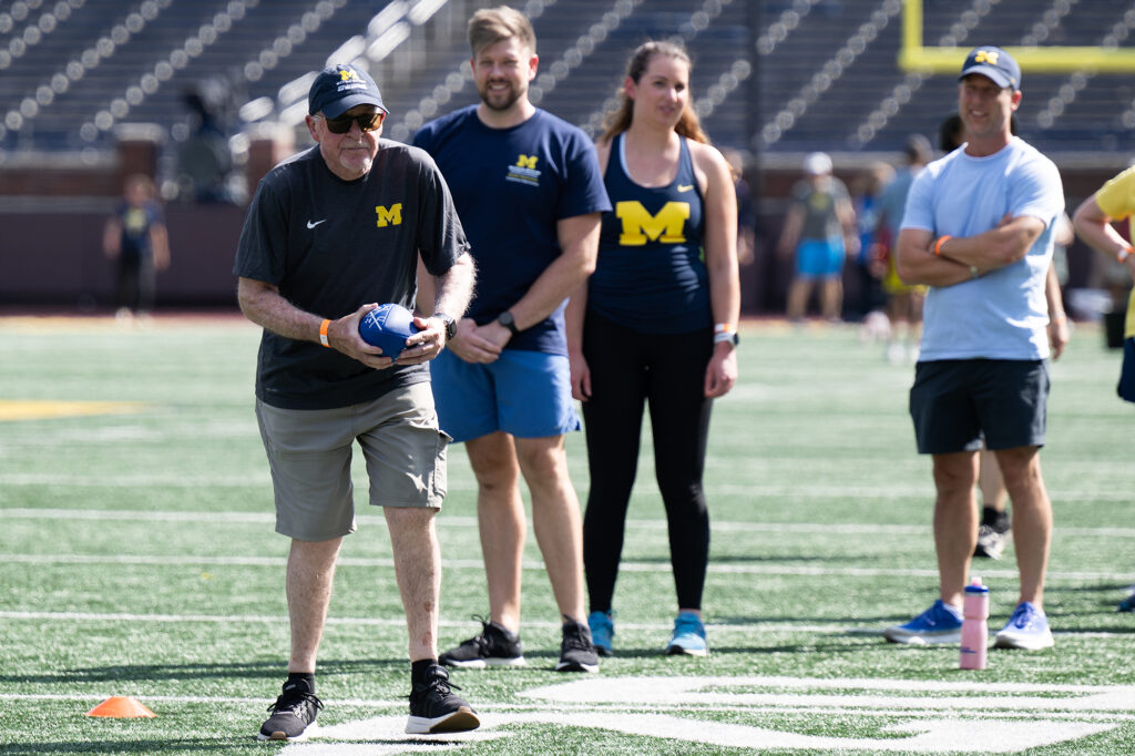 Photo of a man holding a football while three others look on.