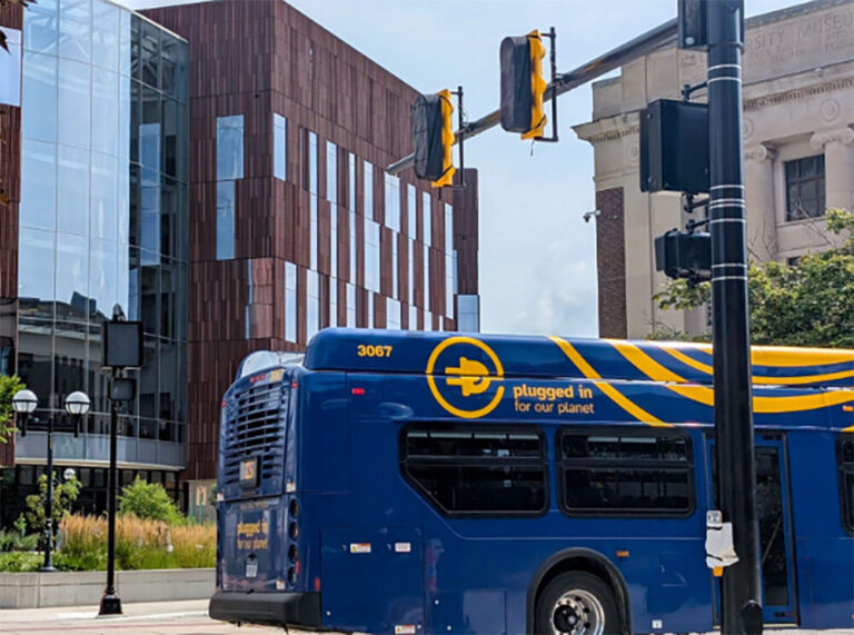 A bus passes by a new traffic signal at a busy crosswalk