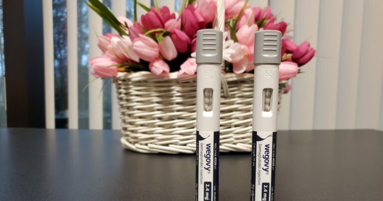 State Treasurer Brad Briner is standing next to Tom Friedman, executive administrator of the N.C. State Health Plan. Someone is holding a large microphone in front of them.