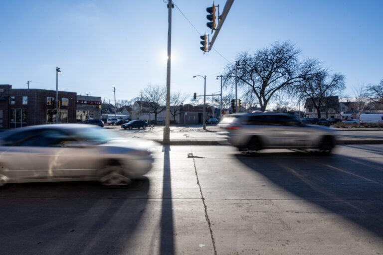 A person drives a car while holding the steering wheel; a speed monitoring device on the dashboard displays a speed of 35 mph.