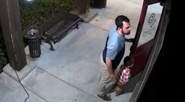 Father And Young Son Stand Guard After Discovering Unlocked Candy Shop