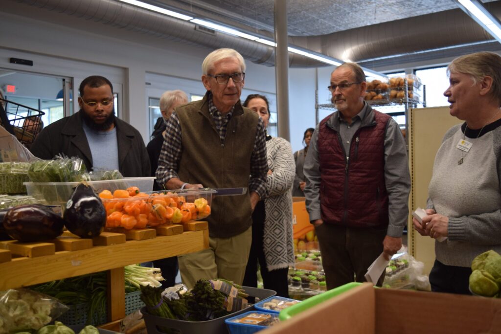 A group of people stand and look at items on store shelves inside a grocery store.