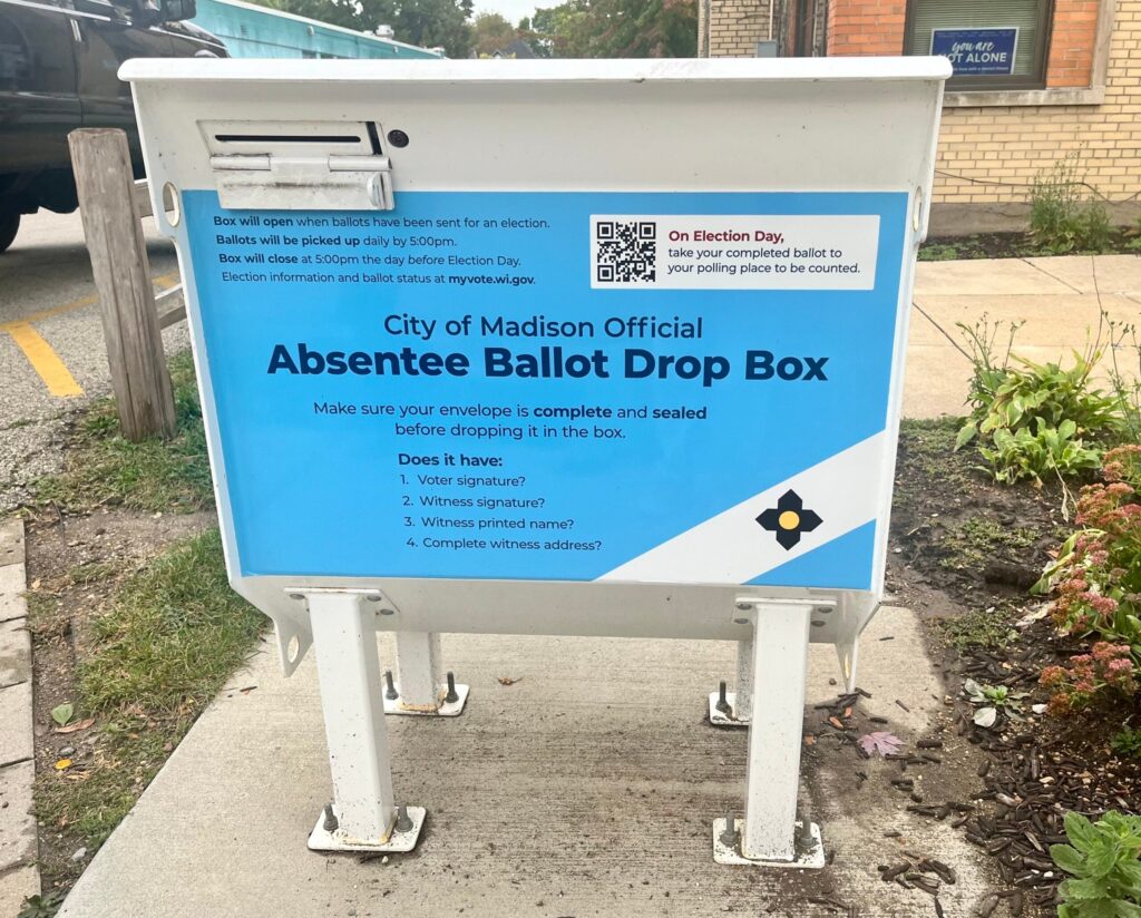 a person places a mail-in ballot in a drop box
