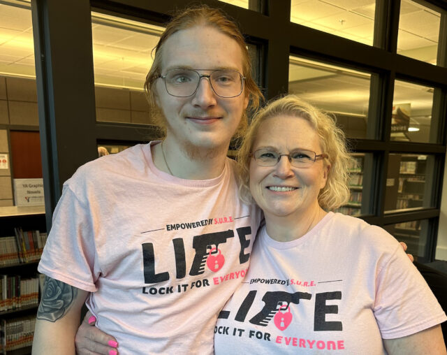A man and his mother stand side by side wearing pink shirts