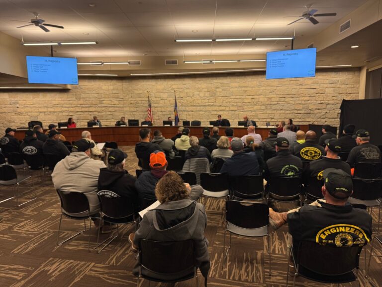 Construction site with large steel framework, a crane, and several workers in safety vests.