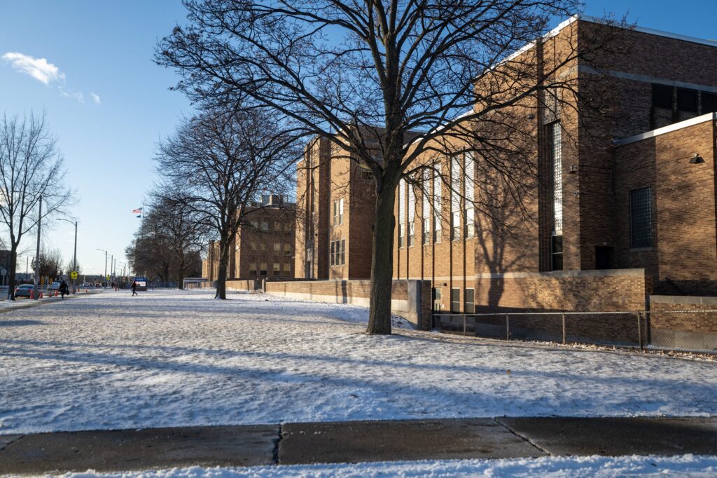 A woman wearing a red sweater and white collared shirt smiles at the camera; her name badge reads Guest Relations.