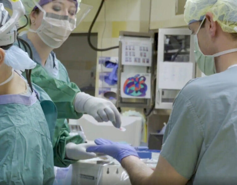 People wearing personal protection equipment work in a lab