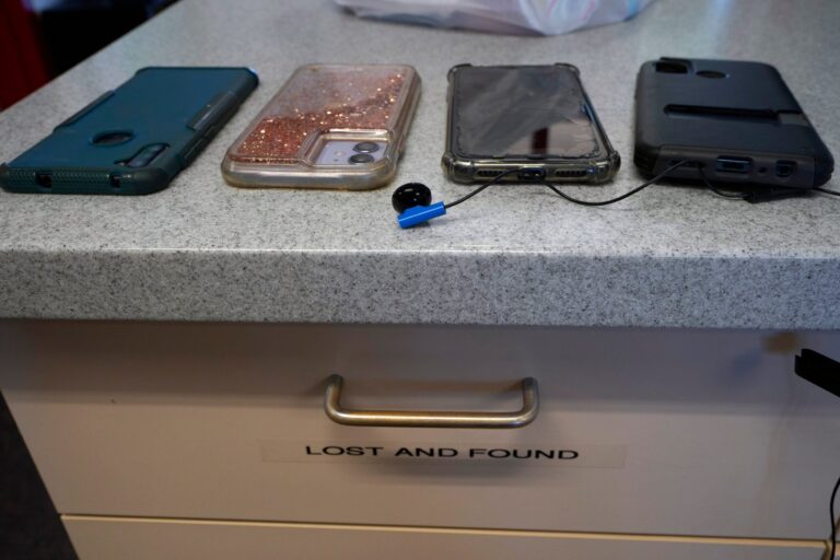 Four smartphones in cases are placed on a countertop labeled Lost and Found.