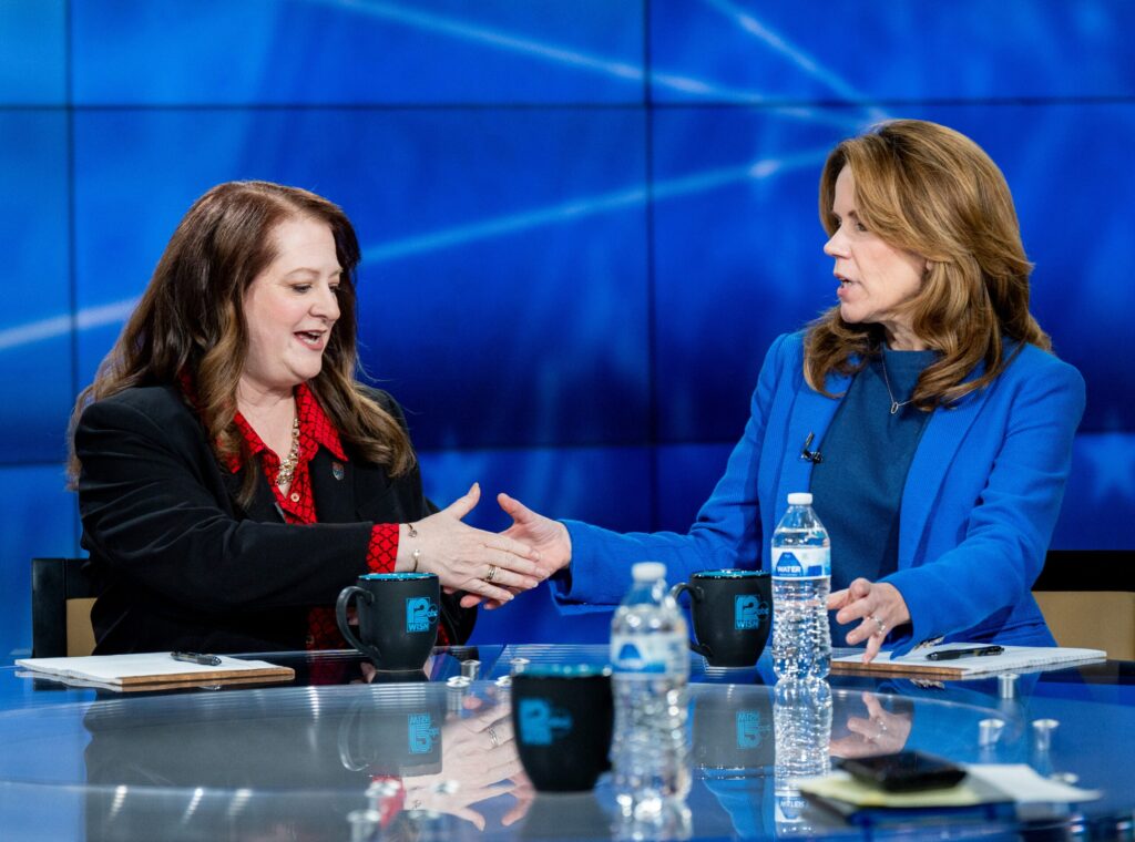 A woman speaks at a podium in front of an American flag to a small seated audience at a Republican Party event in Eau Claire County, Wisconsin.
