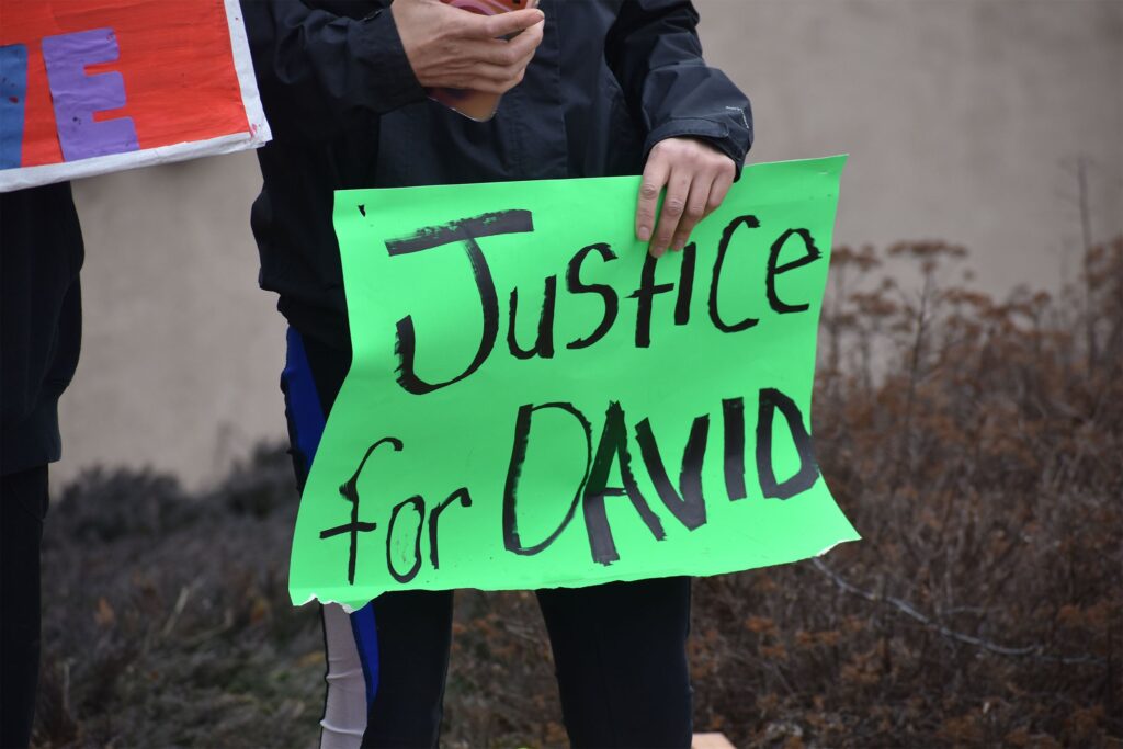 A woman with long dark hair and sunglasses on her head stands outdoors, looking slightly to the side with a neutral expression.