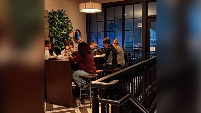 A round sign by a staircase reads: Silent Book Club. Please check in at bookshop front desk. Silent hour @ 6:30 pm.