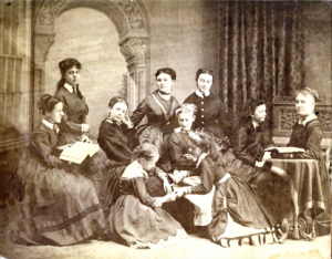 Book cover showing a historic photo of women gathered outdoors and a color photo of a large Victorian house, titled An Elegant Edifice by Mary Elise Antoine.