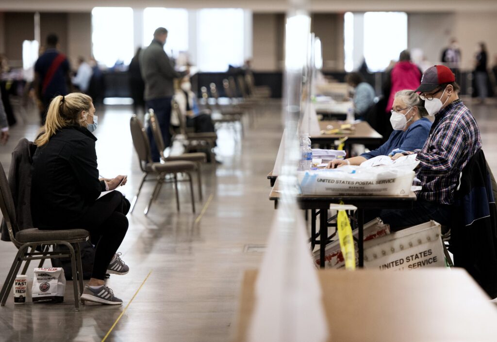 Plexiglass lines a long row of tables as two election officials count ballots