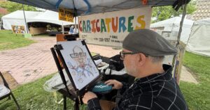 John Krupa begins drawing a caricature of WVIA Chief Engineer Mark Ruddy at the 2026 Fine Arts Fiesta.