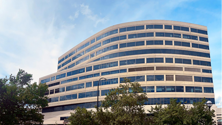 The exterior of a large hospital with blue sky and trees in the foreground