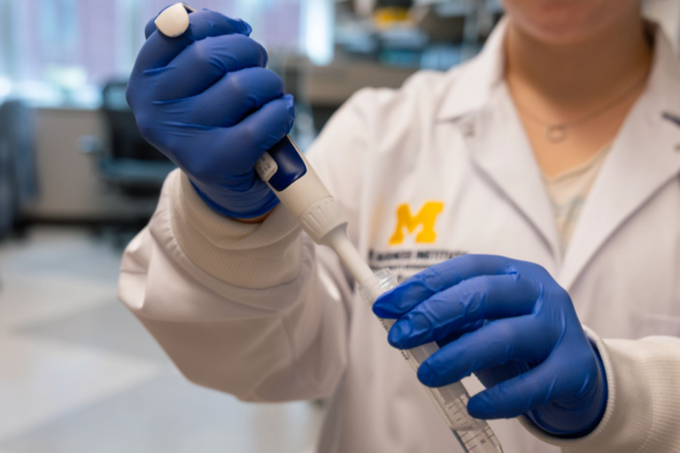 Hands in blue lab gloves connect a piece of medical equipment