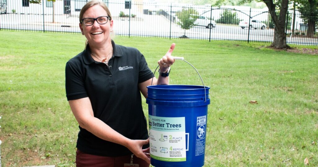 The tree-watering bucket slowly releases water into the ground over a long period of time.