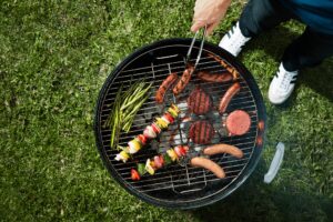 Record-High Costs for Wisconsins July 4th Cookout Survey Reveals - Common Good News A man uses tongs to rotate food on a grill.