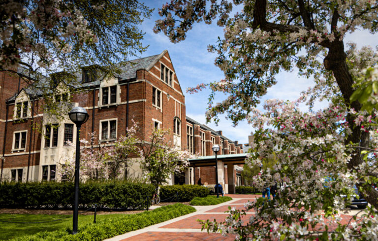 Photo of the Michigan League building with flowering trees in the foreground