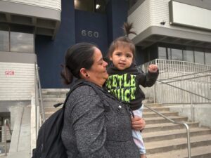 A mother and daughter are pictured at a protest against arrests of immigrants at green card appointments in Salt Lake City. Two lawsuits filed Monday challenge new federal guidance that could affect green card applicants who have used Medicaid or food assistance. (Photo by Annie Knox, Utah News Dispatch)