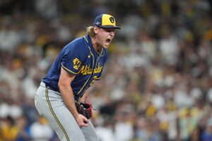 A Milwaukee Brewers baseball player in a blue and yellow uniform running toward first base while dropping his bat.