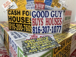 A collection of signs advertising cash for homes is shown earlier this month at an event in Kansas City, Missouri, celebrating a new state law regulating real estate wholesalers. Critics say these businesses can be predatory, especially for poor, minority and older homeowners. (Photo by Kevin Hardy/Stateline)