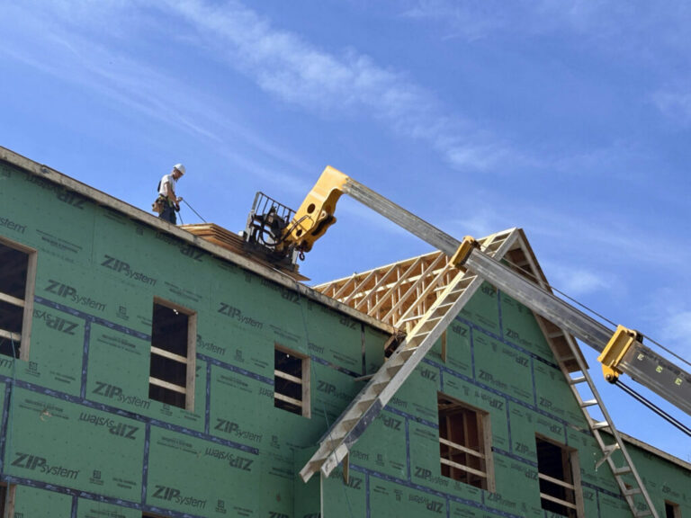 A construction worker retrieves plywood sheets lifted to the roof of a an affordable housing complex for seniors under construction in Portsmouth, Rhode Island. It